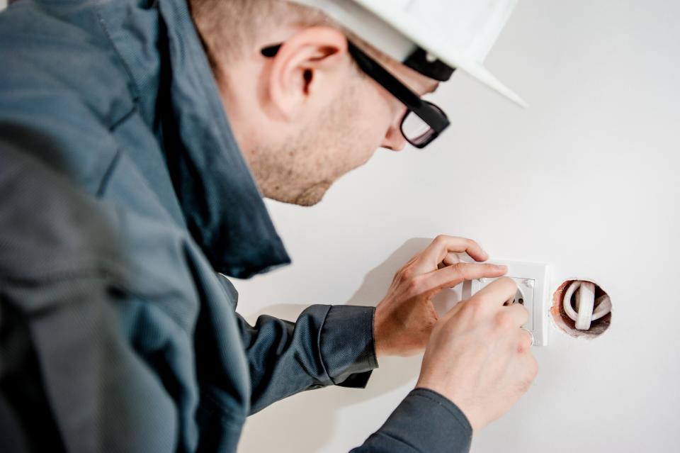 An Ace Electric technician working on a wall device
